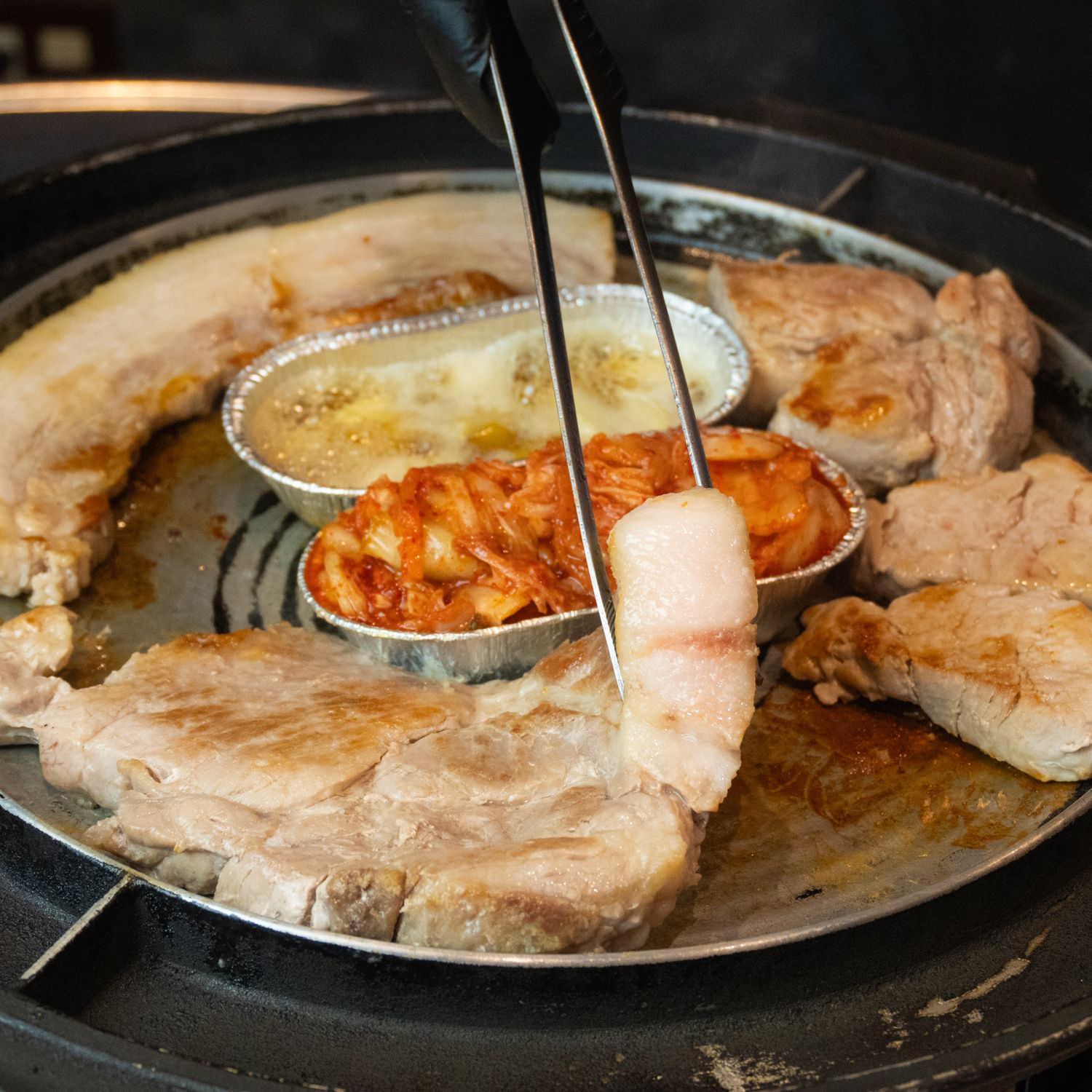 トングで豚肉を焼いている様子